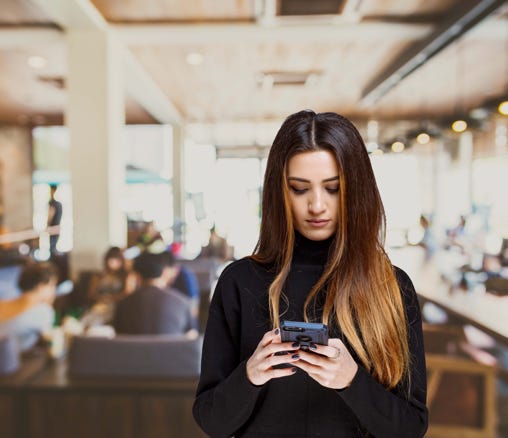 Barista on her phone inside a busy coffee shop