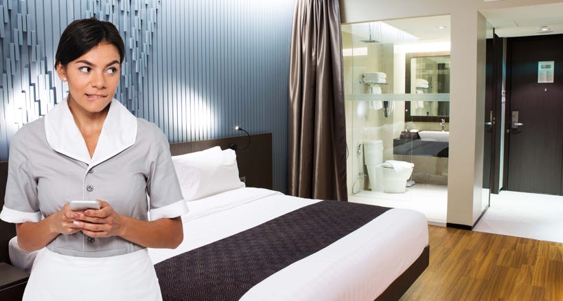 Hotel housekeeper on her phone in a guest room