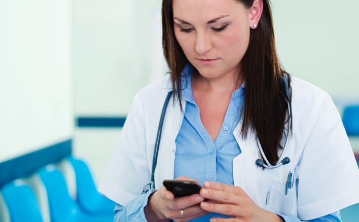 Nurse checking her phone in a clinic hallway